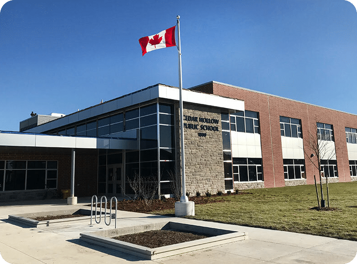 A picturesque view of Cedar Hollow School, surrounded by lush greenery and a clear blue sky, showcasing its welcoming facade